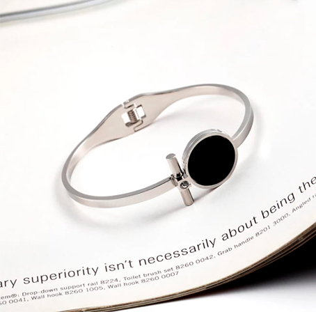 Pulsera rígida redonda en acero con adorno disco negro y pequeña circonita.